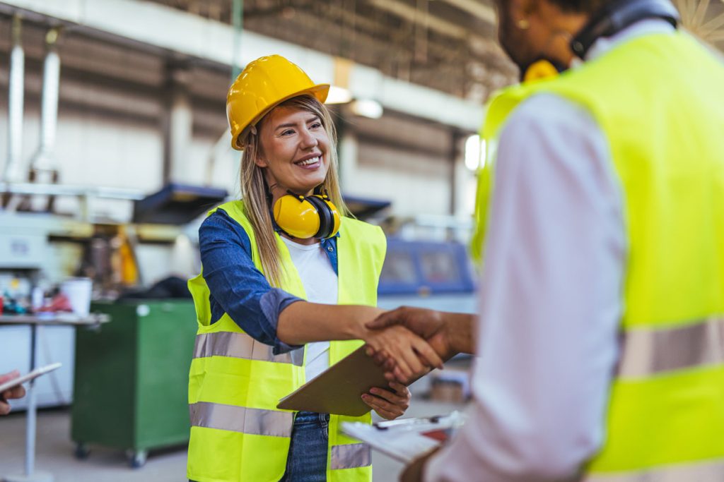 coworkers shake hands in a factory setting
